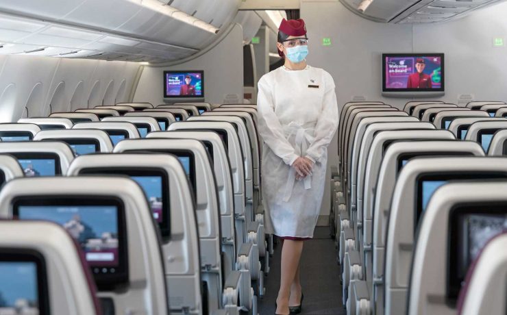 a woman wearing a mask and standing in a plane
