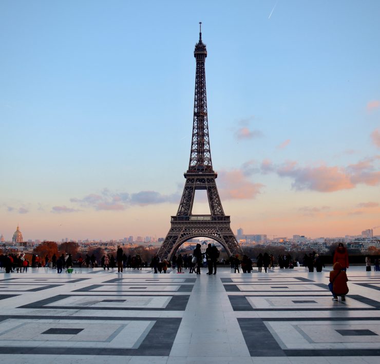 a large metal tower with people in front of it with Eiffel Tower in the background
