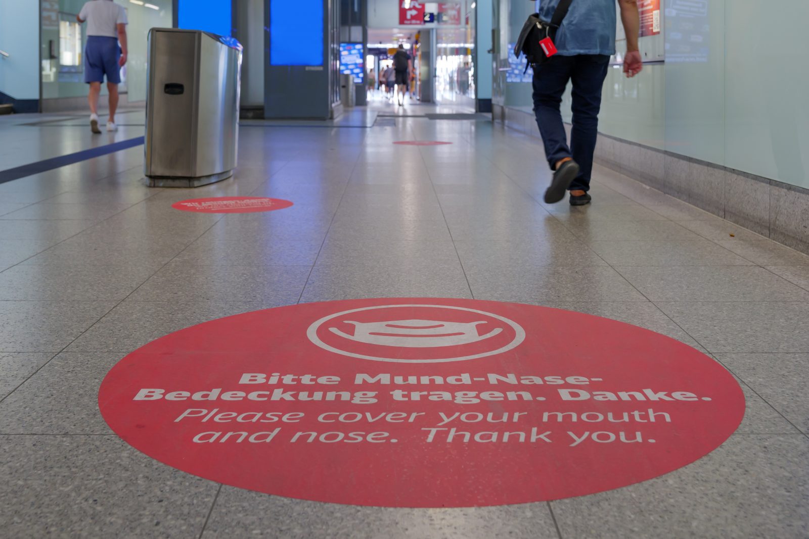 a person walking in a hallway with red circle signs on the floor