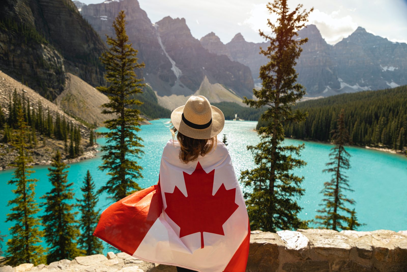 a woman with a flag on her back looking at a lake
