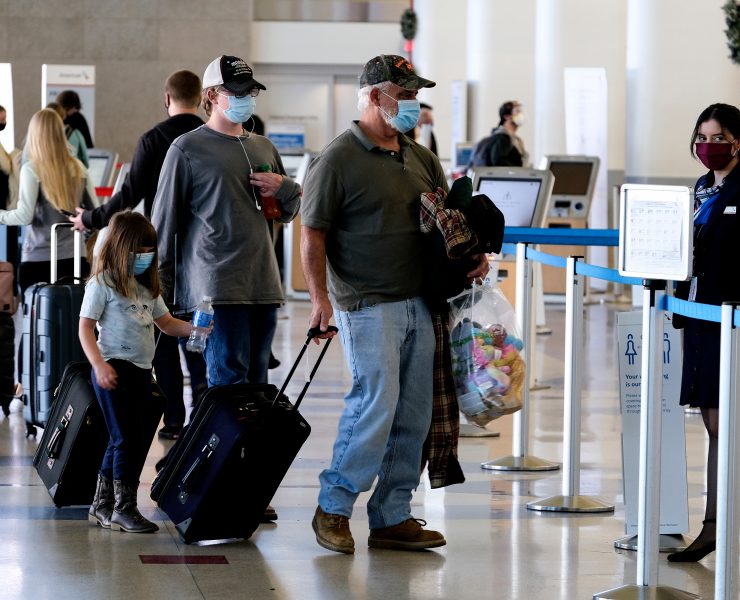people with face masks and luggage in an airport