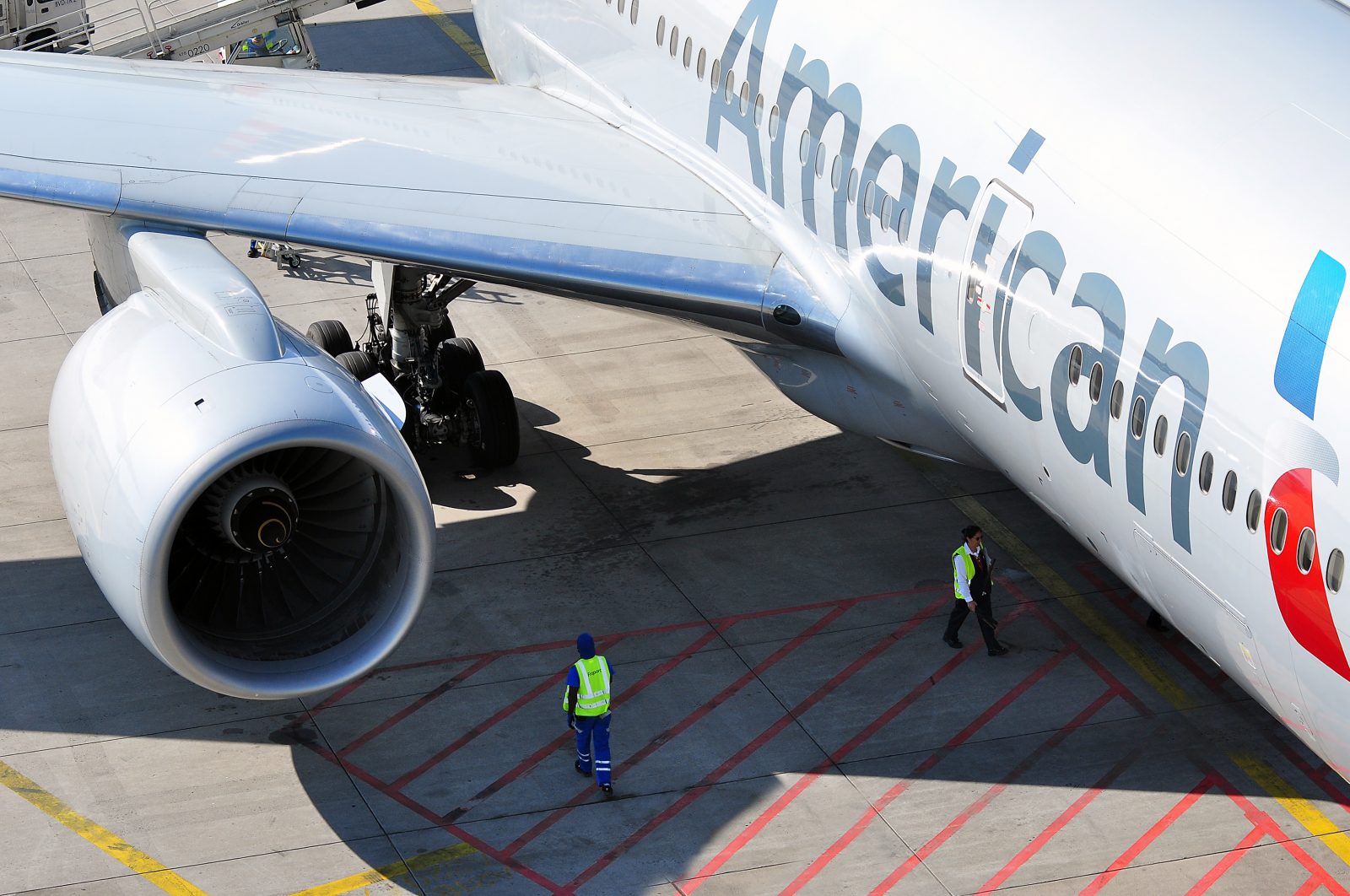 american airlines aircraft on the tarmac with ground staff stood under wing