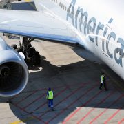 american airlines aircraft on the tarmac with ground staff stood under wing