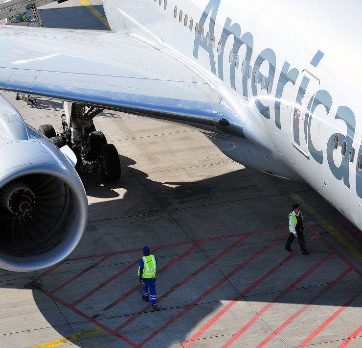 american airlines aircraft on the tarmac with ground staff stood under wing