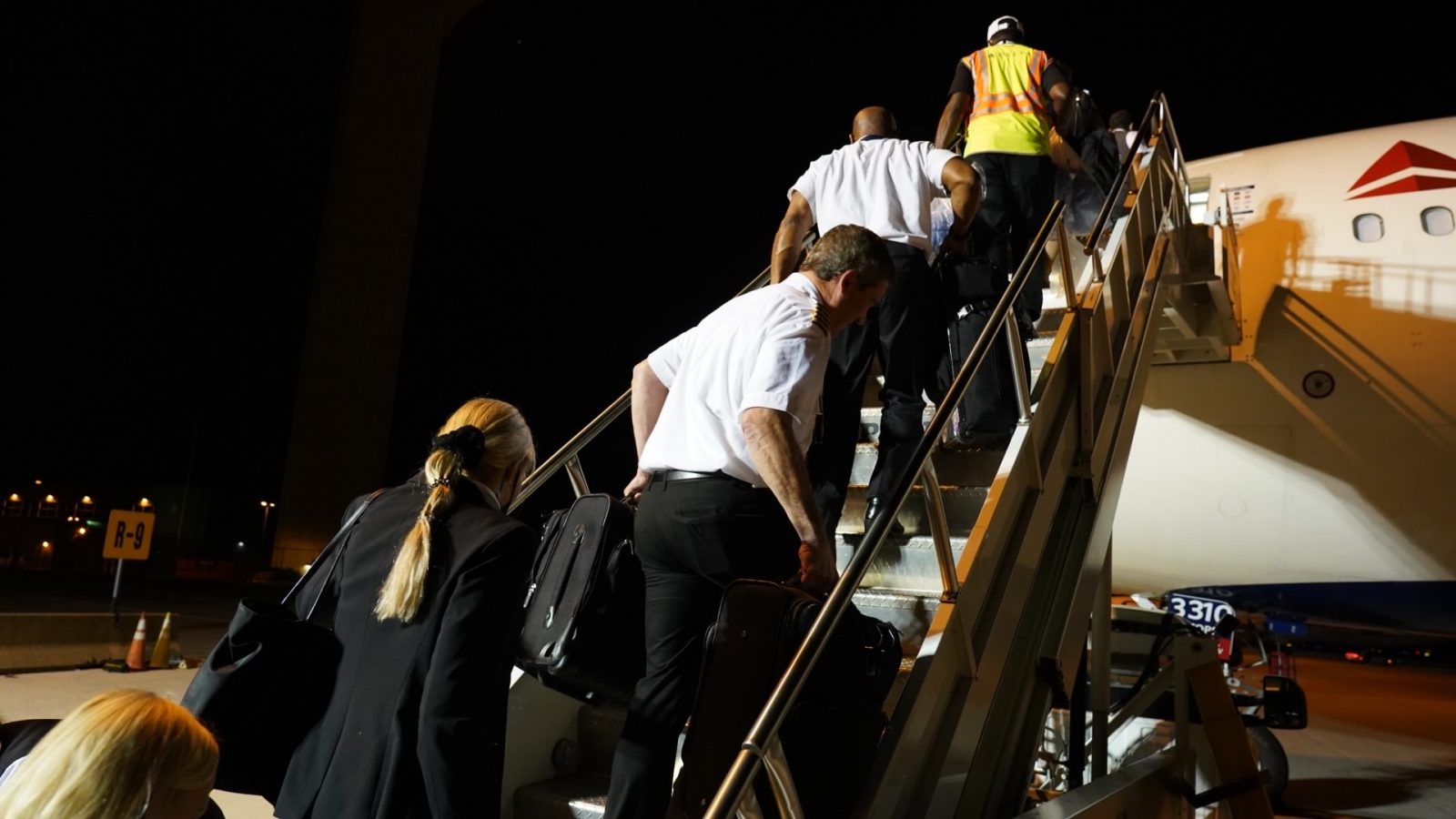 delta air lines employees walk up steps to plane