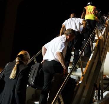 delta air lines employees walk up steps to plane