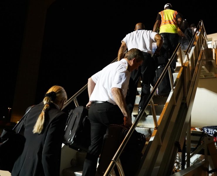 delta air lines employees walk up steps to plane