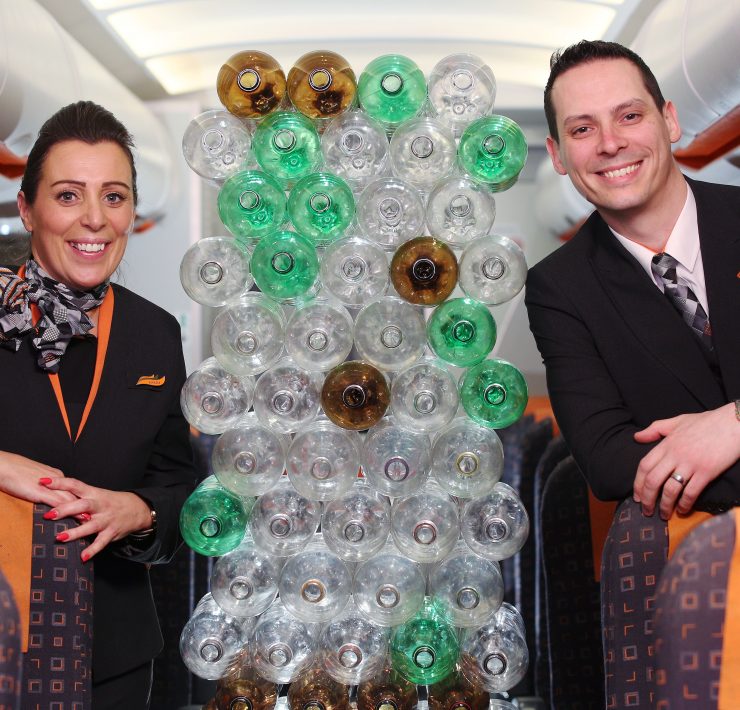 a man and woman standing next to a sculpture of plastic bottles