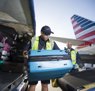 a group of men loading luggage into an airplane