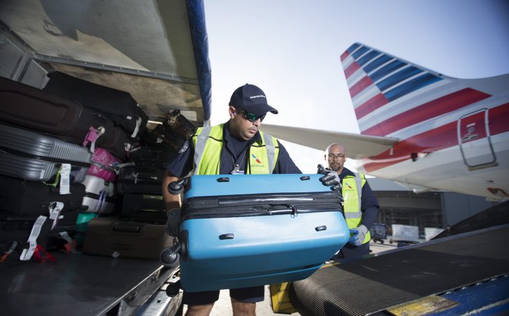 a group of men loading luggage into an airplane