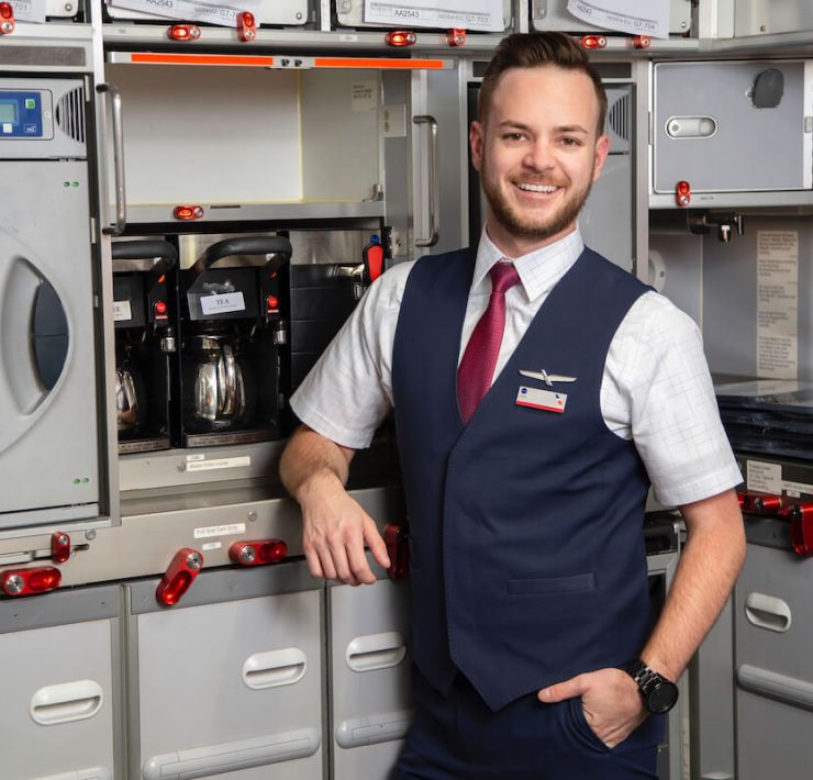 a man in a vest and tie standing in front of a cabinet