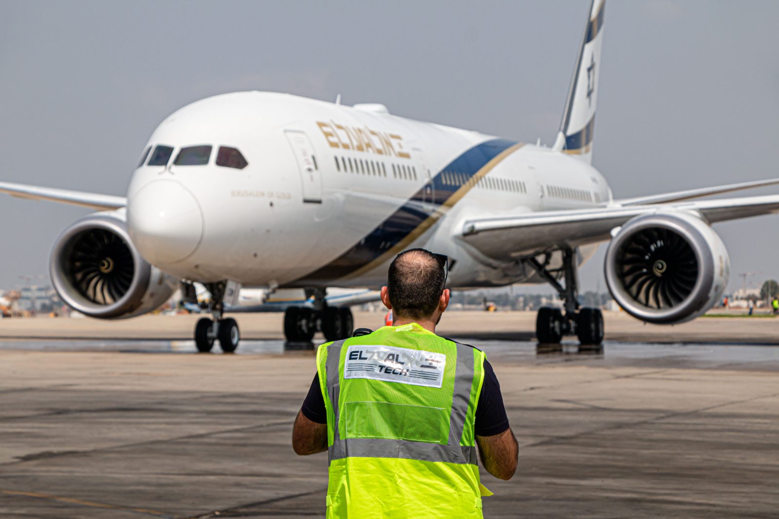 a man in a reflective vest standing in front of an airplane