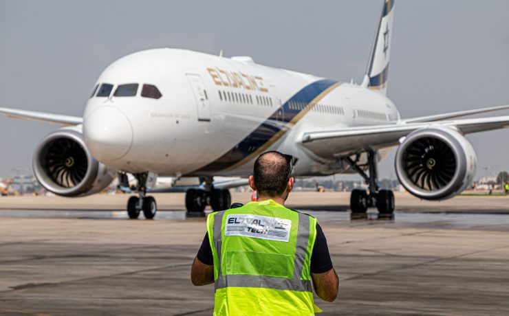 a man in a reflective vest standing in front of an airplane