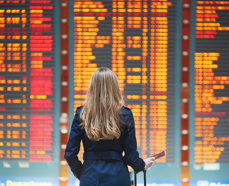 a woman looking at a flight information board