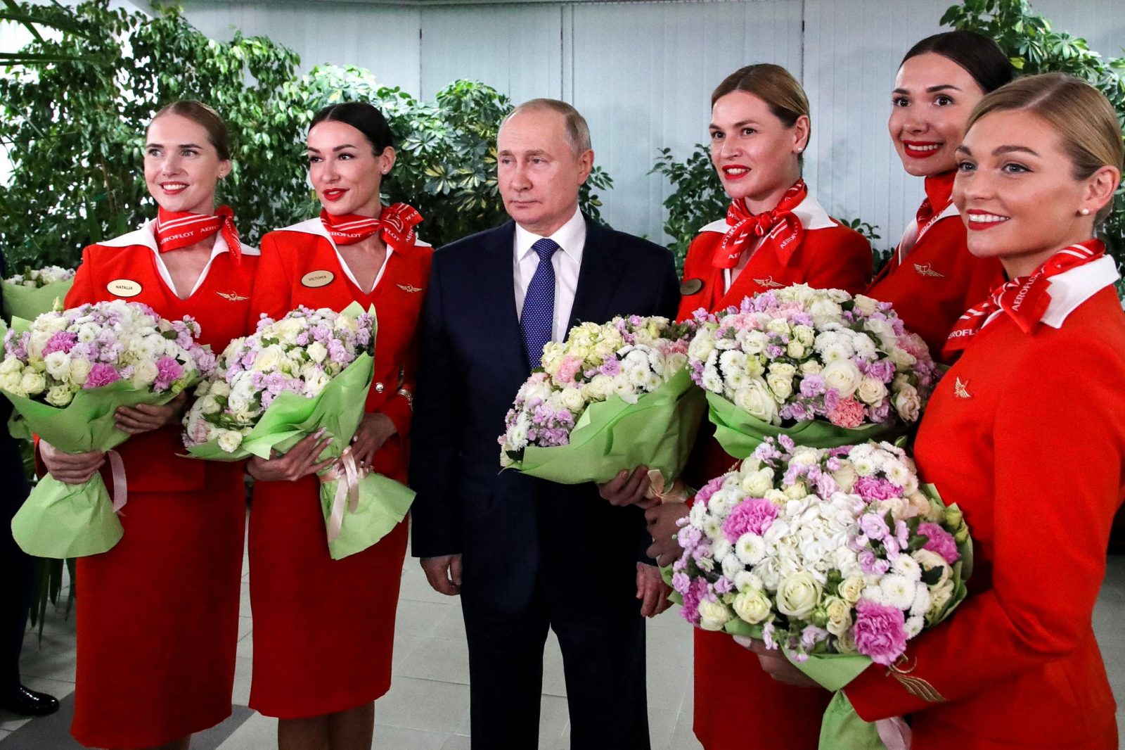 a man in a suit and a group of women holding flowers