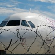 a white airplane behind a barbed wire fence