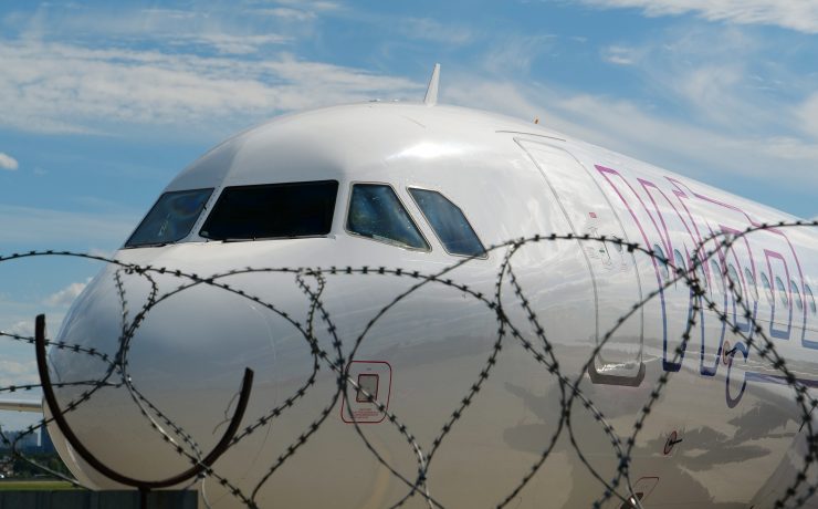 a white airplane behind a barbed wire fence
