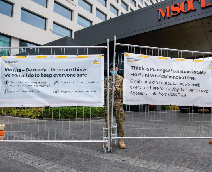 a person in a mask standing behind a fence with signs