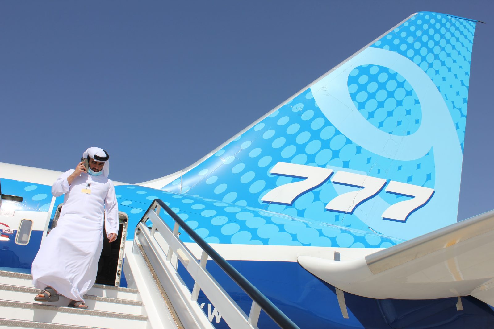 a man in a white suit walking up the stairs of an airplane