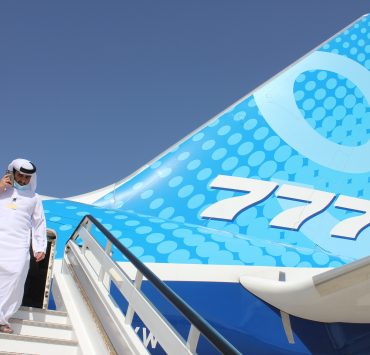 a man in a white suit walking up the stairs of an airplane