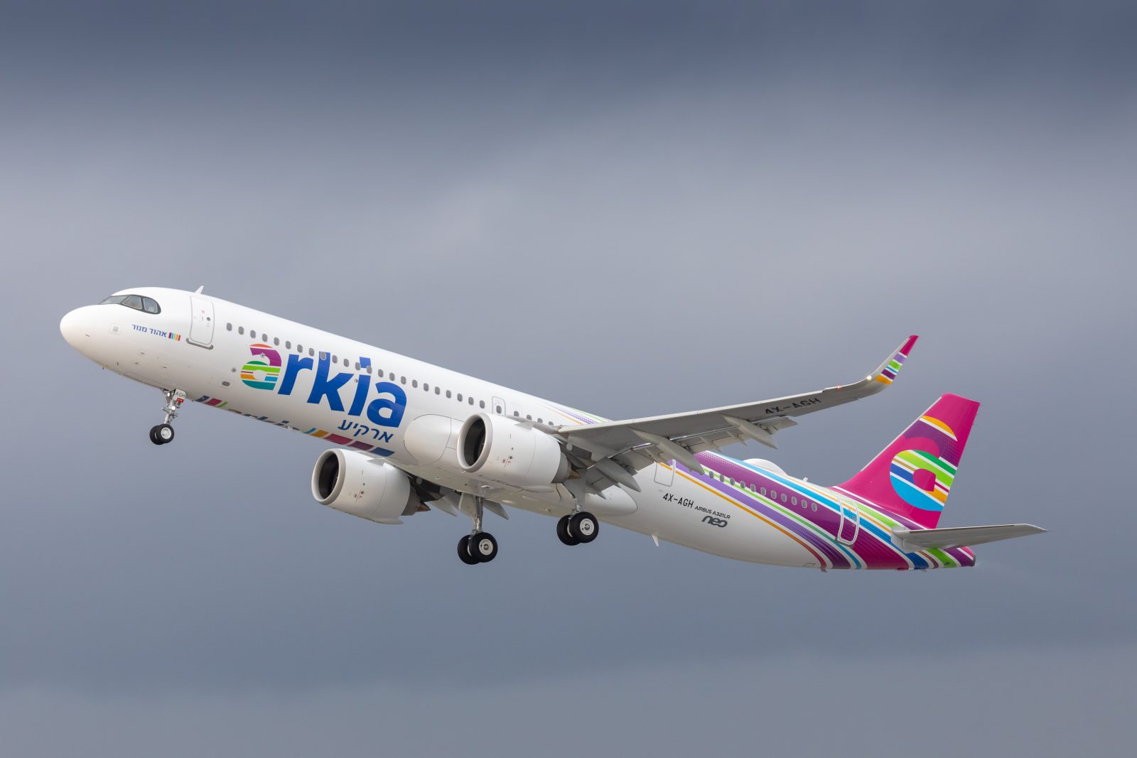 a white airplane with pink and purple stripes flying in the sky