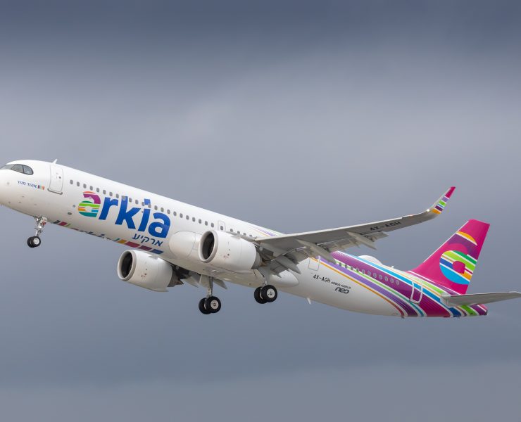a white airplane with pink and purple stripes flying in the sky