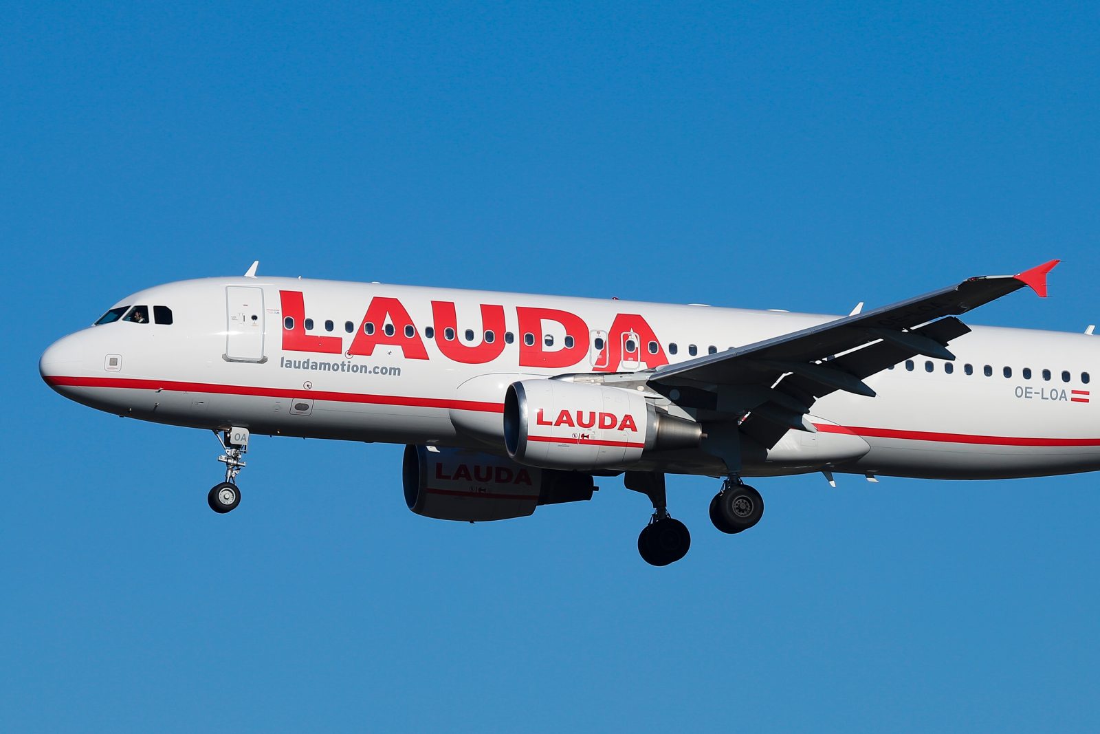 a white airplane with red writing flying in the sky