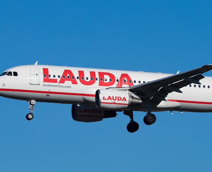 a white airplane with red writing flying in the sky