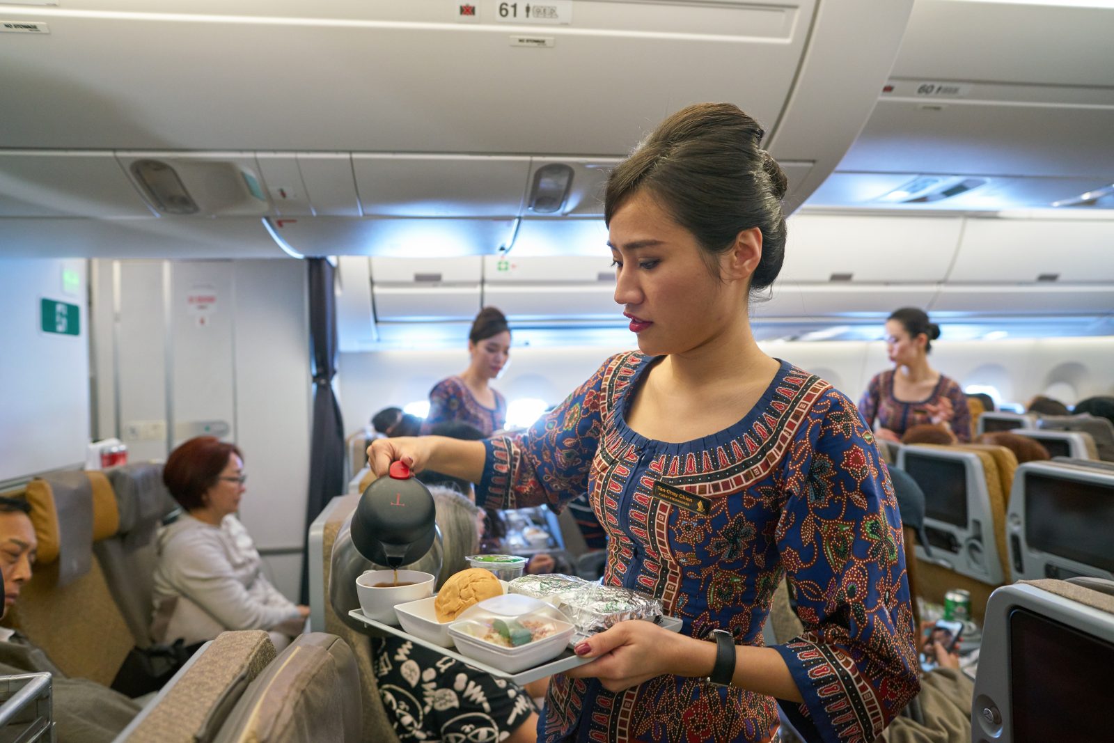 a woman pouring tea into a tray on an airplane