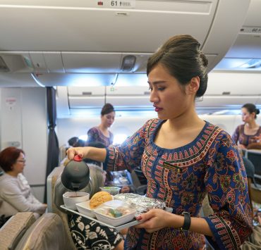 a woman pouring tea into a tray on an airplane