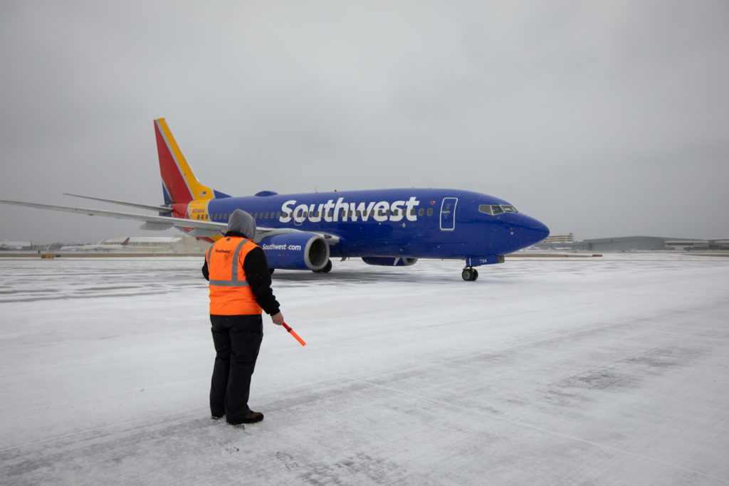 a person standing in the snow next to a blue airplane