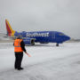a person standing in the snow next to a blue airplane