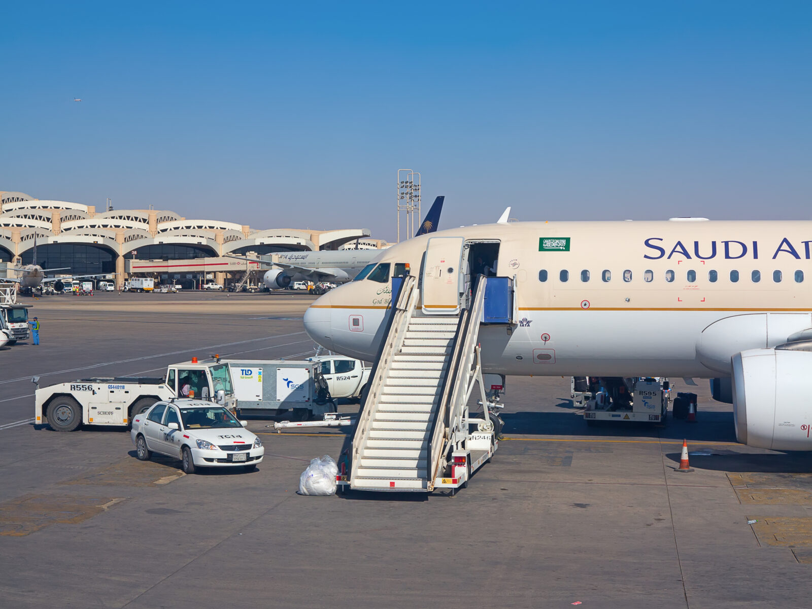 a plane with a staircase and cars on the tarmac