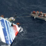 a group of people in an inflatable boat with a plane in the water