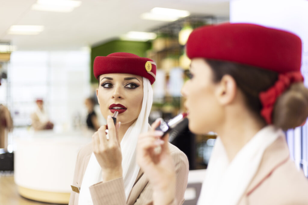 a woman in a red hat applying lipstick