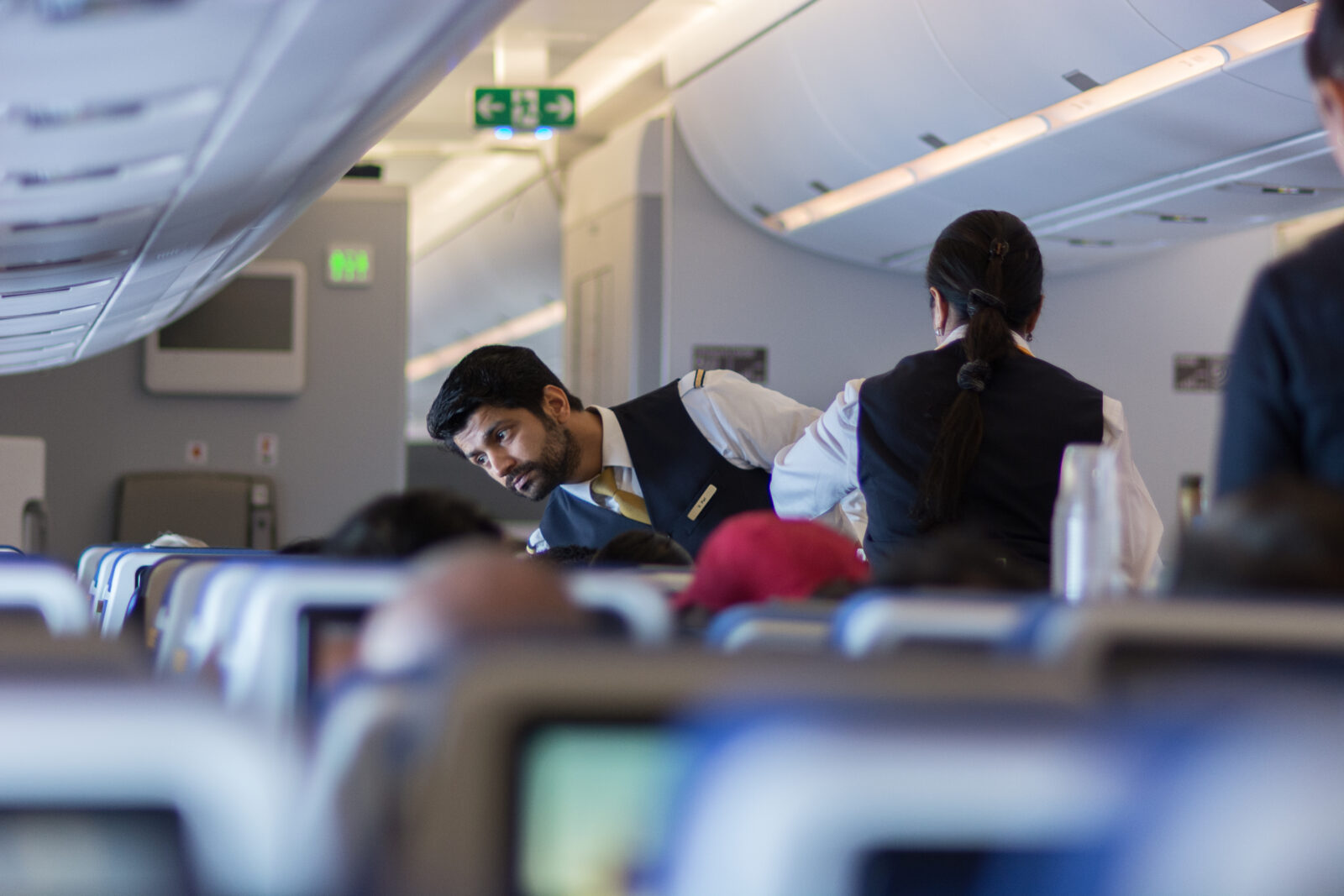 a man in a vest and vest standing next to a woman in an airplane