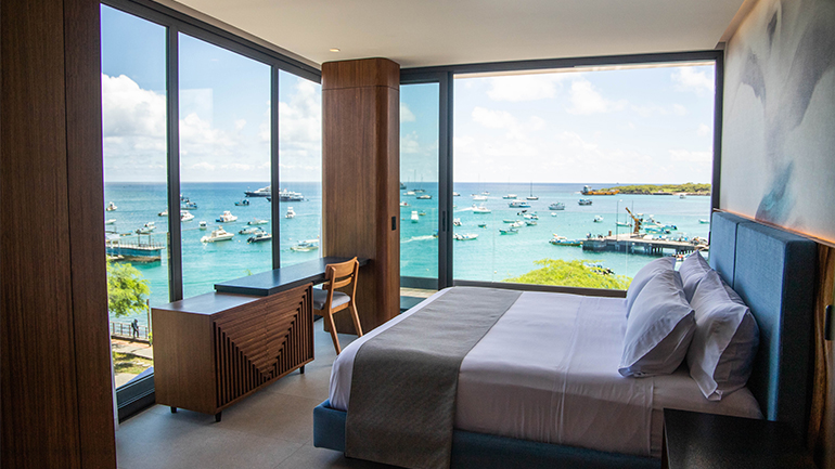 a room with a bed and a view of the ocean