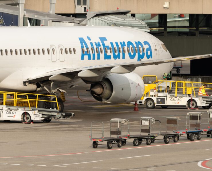 a large airplane with luggage carts and a building