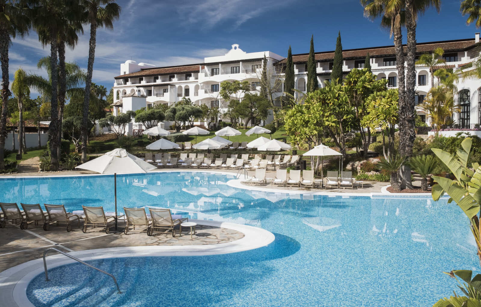 a pool with chairs and umbrellas in front of a building