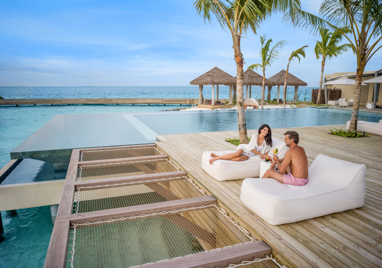 a man and woman sitting on lounge chairs next to a pool