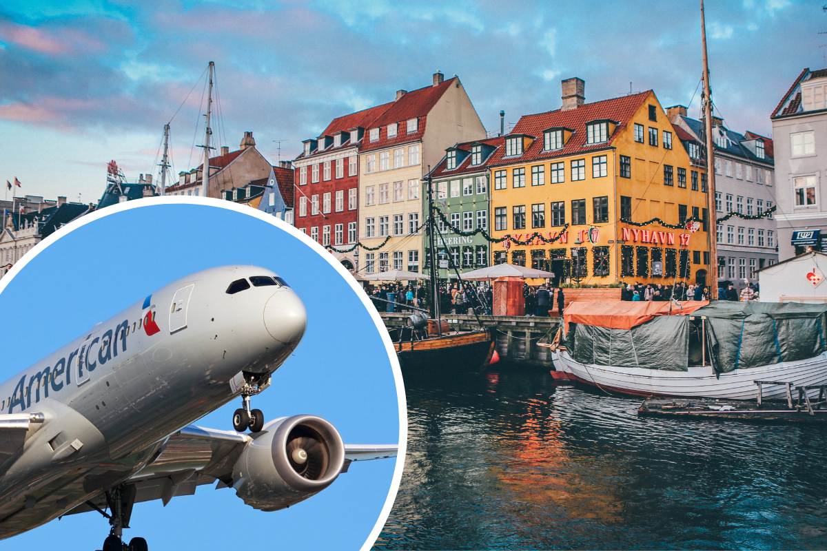 a plane flying over water with buildings and boats in the background