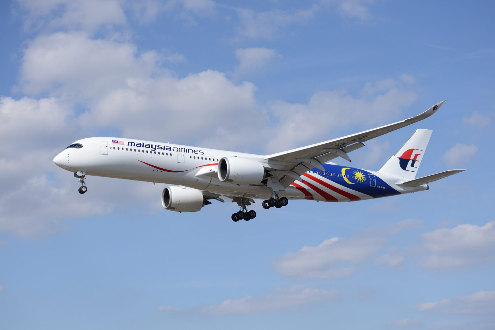 a white airplane with red and blue stripes flying in the sky