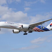 a white airplane with red and blue stripes flying in the sky