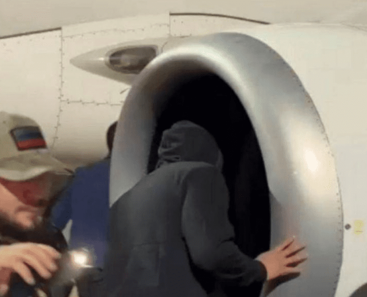 a person in a black hoodie coming out of an airplane