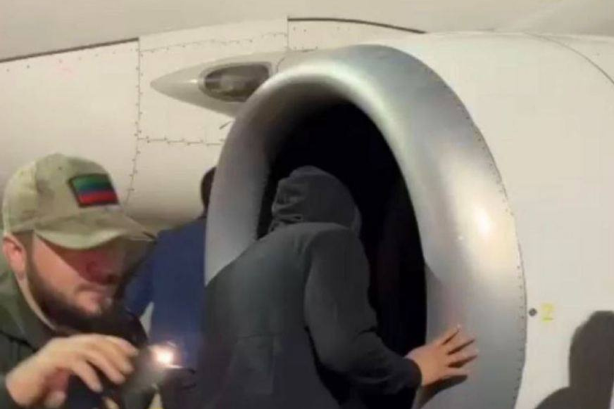 a person in a black hoodie coming out of an airplane