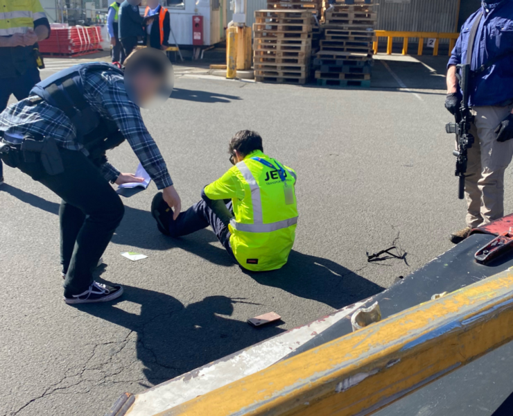 a man sitting on the ground with a man in a safety vest