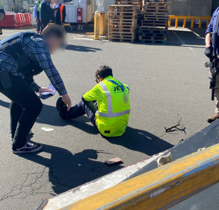 a man sitting on the ground with a man in a safety vest
