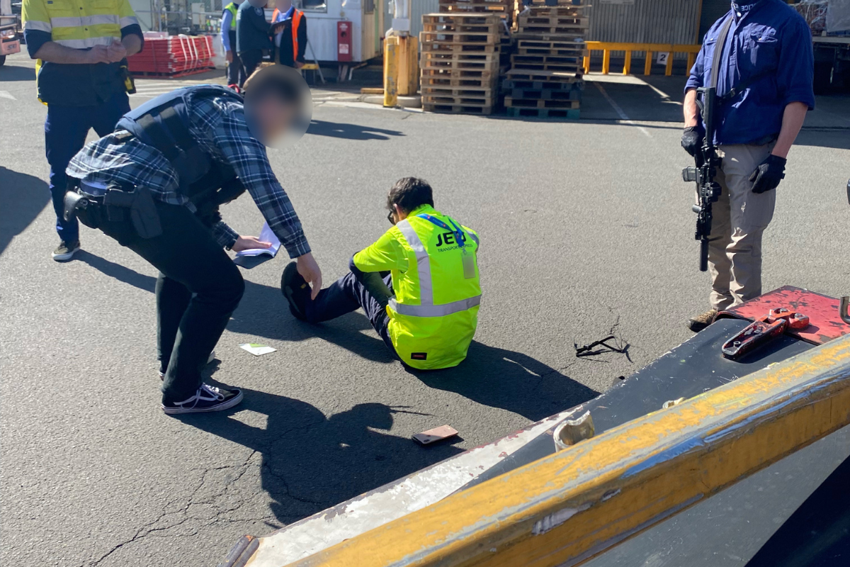 a man sitting on the ground with a man in a safety vest