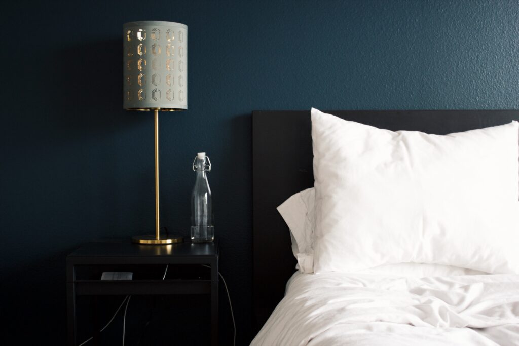 a lamp on a table next to a bed