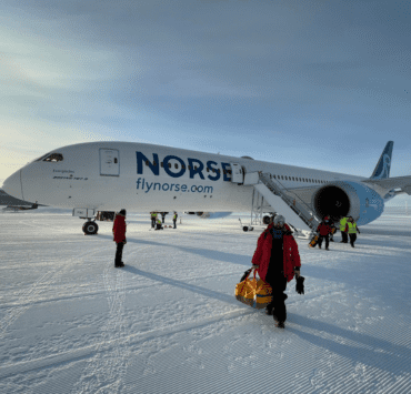 a plane with people standing in the snow